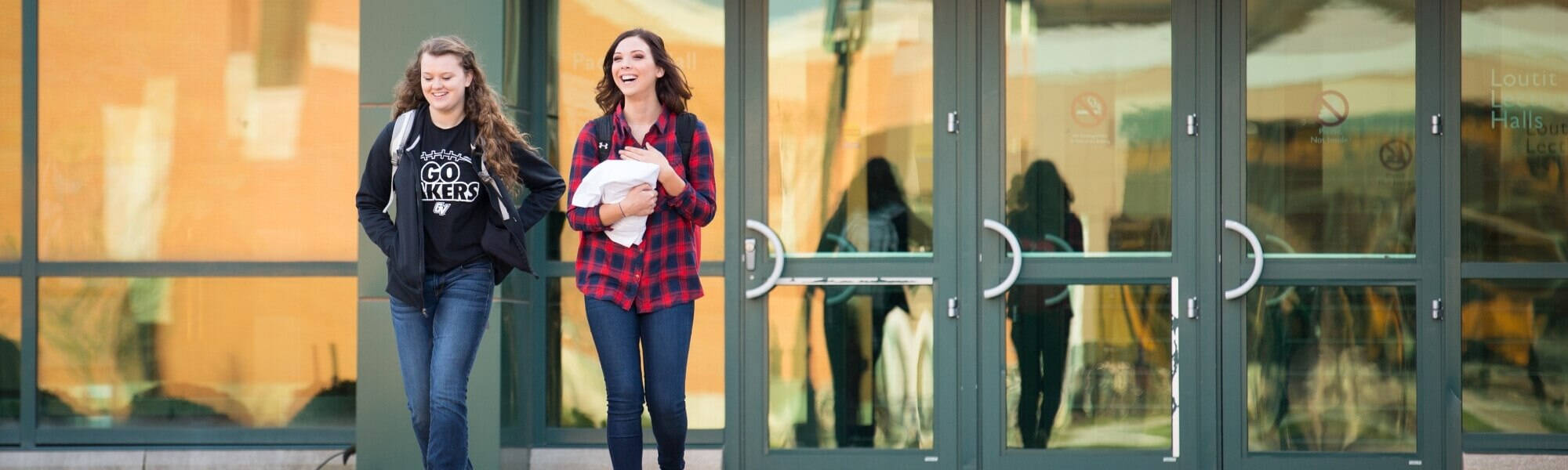 Two students walking outside of the Student Services building
